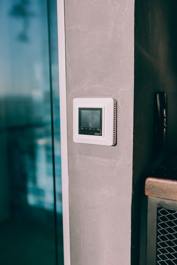 Smart thermostat mounted on a concrete wall, reflecting modern interior design with natural light.